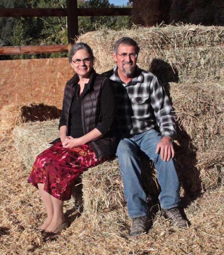 The Feed Bin owners sitting on a bale of hay in a barn
